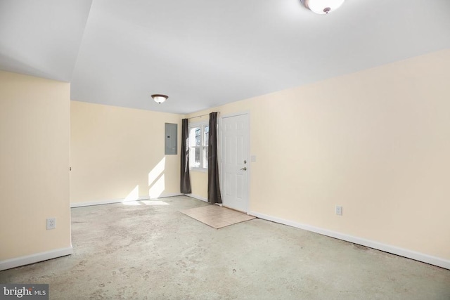 spare room with electric panel, baseboards, and concrete floors