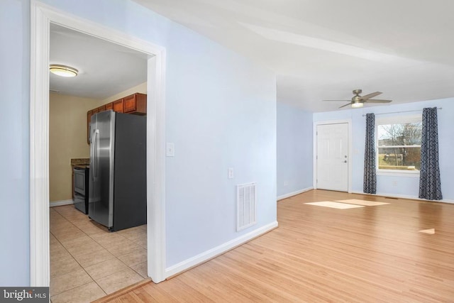 interior space featuring visible vents, light wood-style flooring, a ceiling fan, and baseboards