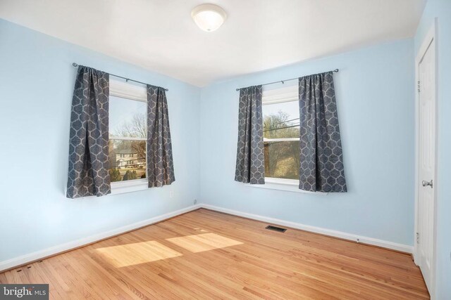 spare room featuring visible vents, baseboards, and wood finished floors