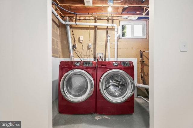 clothes washing area with concrete block wall, laundry area, and washer and clothes dryer