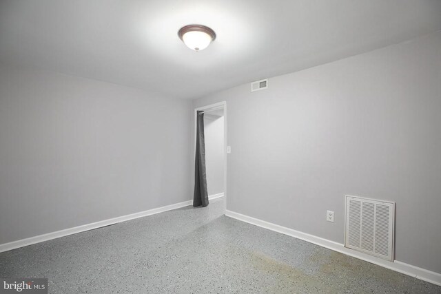 empty room with visible vents, baseboards, and speckled floor