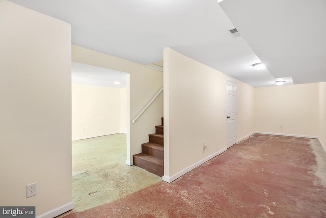 finished below grade area featuring visible vents, baseboards, and stairs