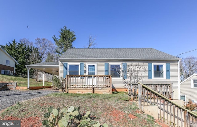 view of front of house with central AC unit, an attached carport, gravel driveway, and roof with shingles