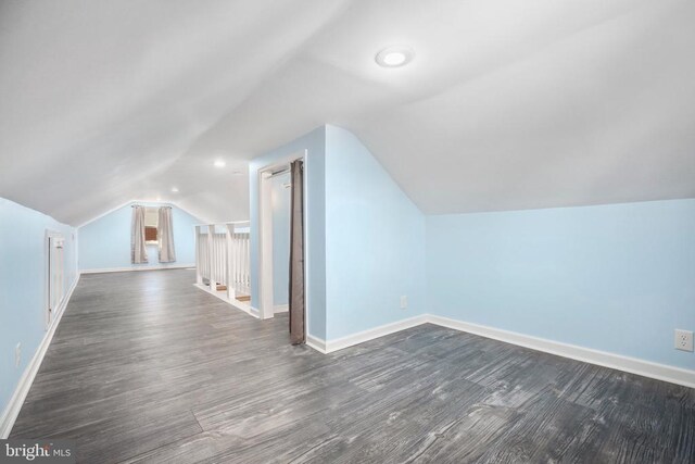 additional living space featuring dark wood-type flooring, baseboards, and vaulted ceiling