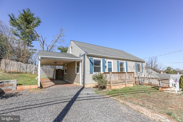 view of front of home with driveway, fence, a shingled roof, a wooden deck, and a carport