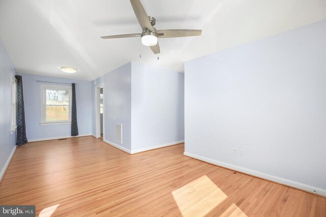 spare room featuring visible vents, baseboards, wood finished floors, and a ceiling fan