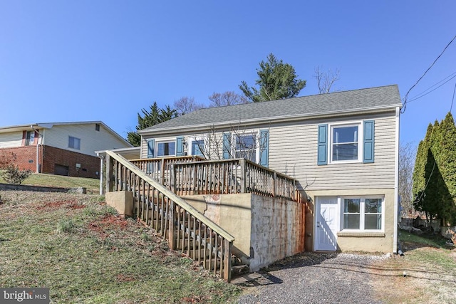 view of front facade with a wooden deck, stairs, and a shingled roof