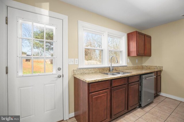 kitchen featuring baseboards, dishwasher, light countertops, light tile patterned floors, and a sink