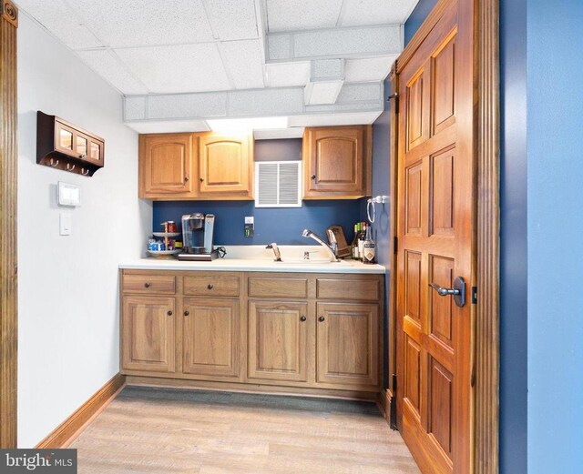 kitchen with a drop ceiling, sink, and light hardwood / wood-style floors