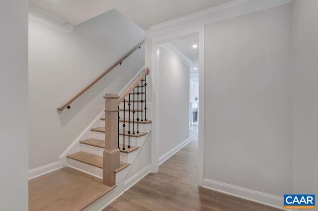 staircase featuring ornamental molding and hardwood / wood-style floors