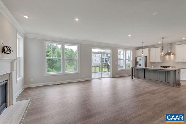 unfurnished living room featuring ornamental molding, a high end fireplace, sink, and light hardwood / wood-style floors