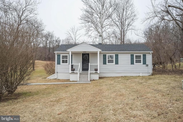 view of front of property featuring a porch, roof with shingles, a chimney, and a front lawn