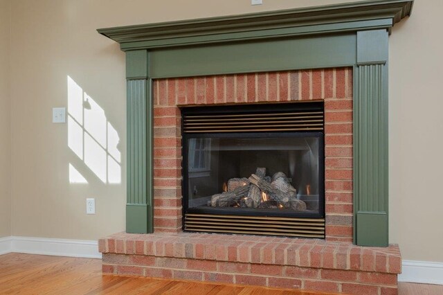 interior details featuring a brick fireplace and wood-type flooring