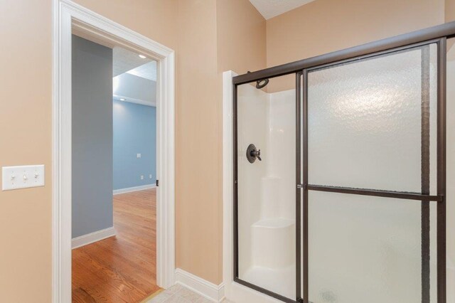 bathroom featuring a shower with shower door and hardwood / wood-style floors