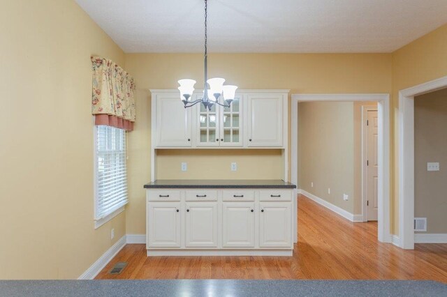 kitchen with hanging light fixtures, a notable chandelier, white cabinets, and light hardwood / wood-style floors