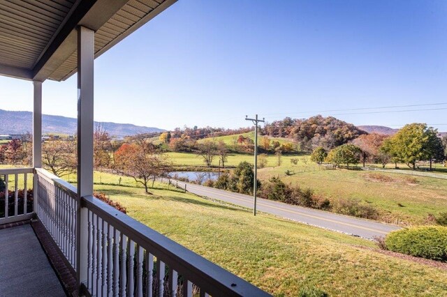 balcony featuring a water and mountain view and a rural view