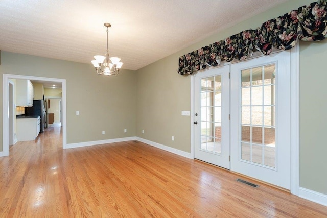 unfurnished dining area featuring a notable chandelier and light wood-type flooring