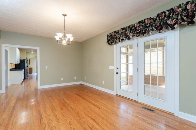 unfurnished dining area featuring a notable chandelier and light wood-type flooring