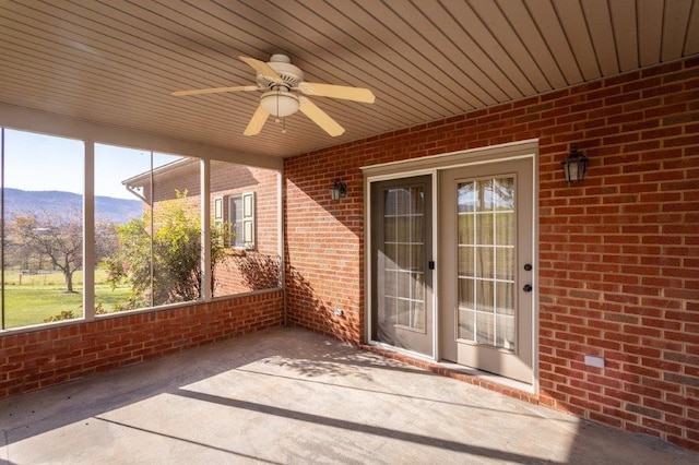 unfurnished sunroom featuring ceiling fan and a mountain view