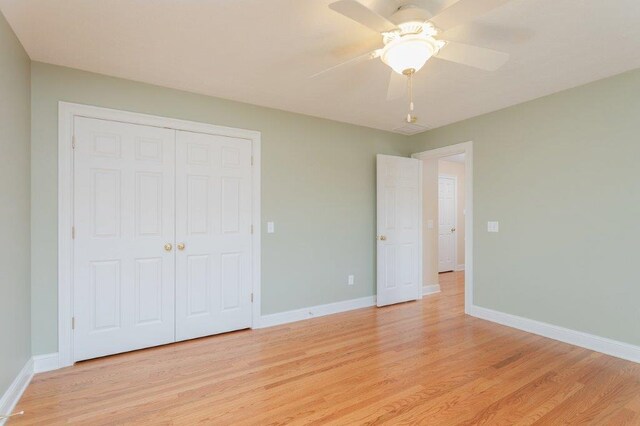 unfurnished bedroom with ceiling fan, light wood-type flooring, and a closet