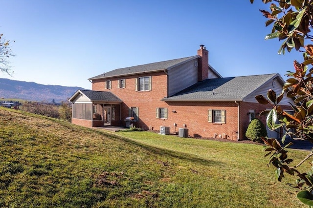 rear view of property with a mountain view, a yard, cooling unit, and a sunroom