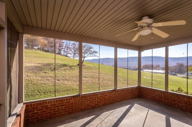 unfurnished sunroom with a mountain view and ceiling fan