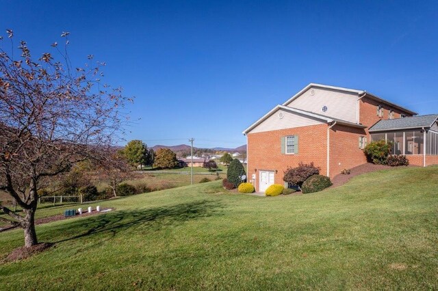 view of side of property with a lawn and a sunroom