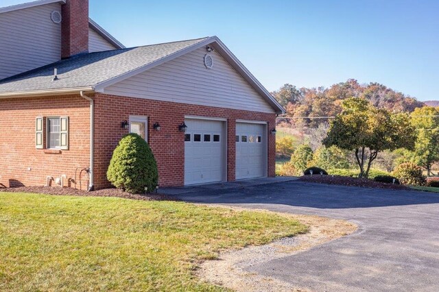 view of side of property featuring a garage and a lawn