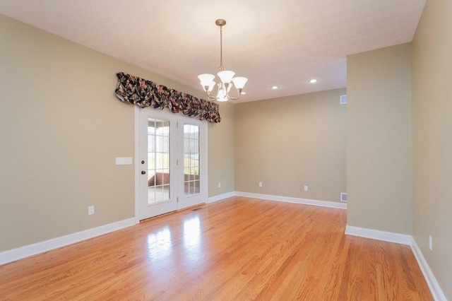 spare room with a chandelier and light hardwood / wood-style floors