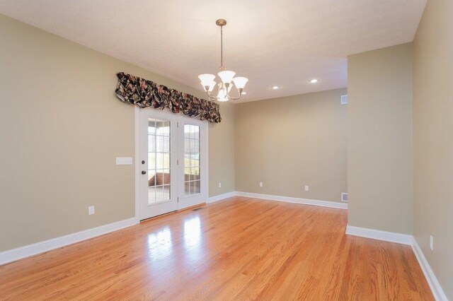 spare room with a chandelier and light hardwood / wood-style floors