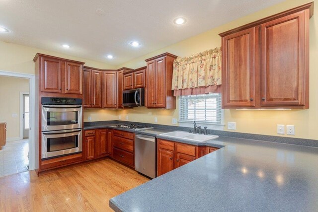 kitchen featuring stainless steel appliances, sink, and light hardwood / wood-style flooring