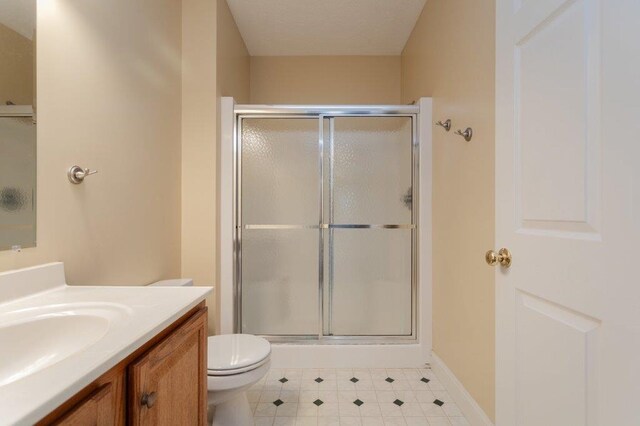 bathroom featuring vanity, toilet, and a shower with shower door