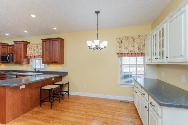 kitchen featuring white cabinetry, a kitchen bar, light wood-type flooring, and pendant lighting