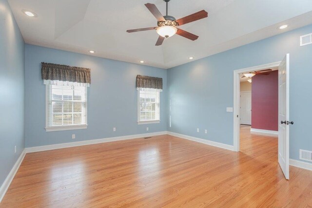 unfurnished room with ceiling fan, a raised ceiling, and light wood-type flooring