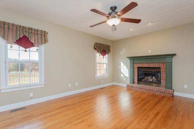 unfurnished living room featuring a fireplace, light hardwood / wood-style flooring, and ceiling fan