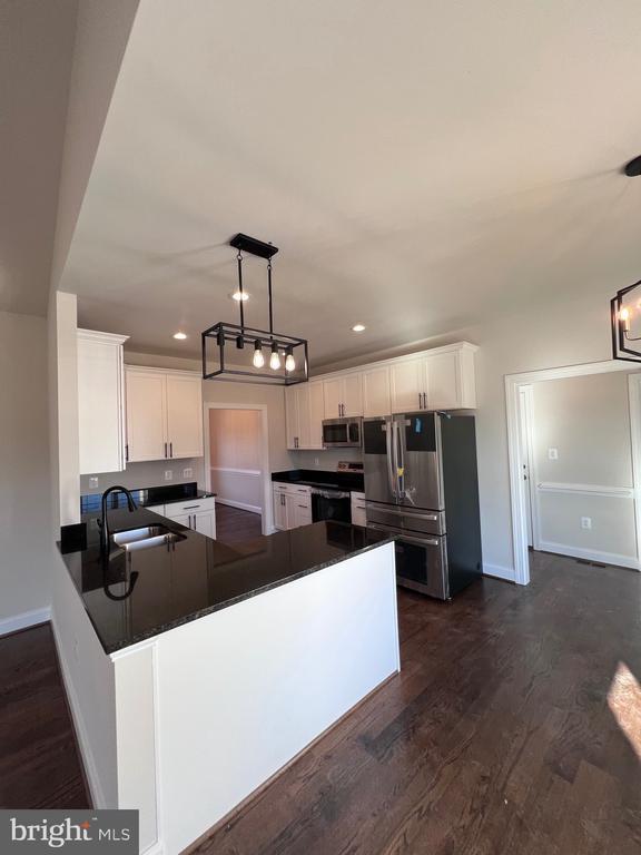 kitchen with decorative light fixtures, sink, white cabinets, kitchen peninsula, and stainless steel appliances