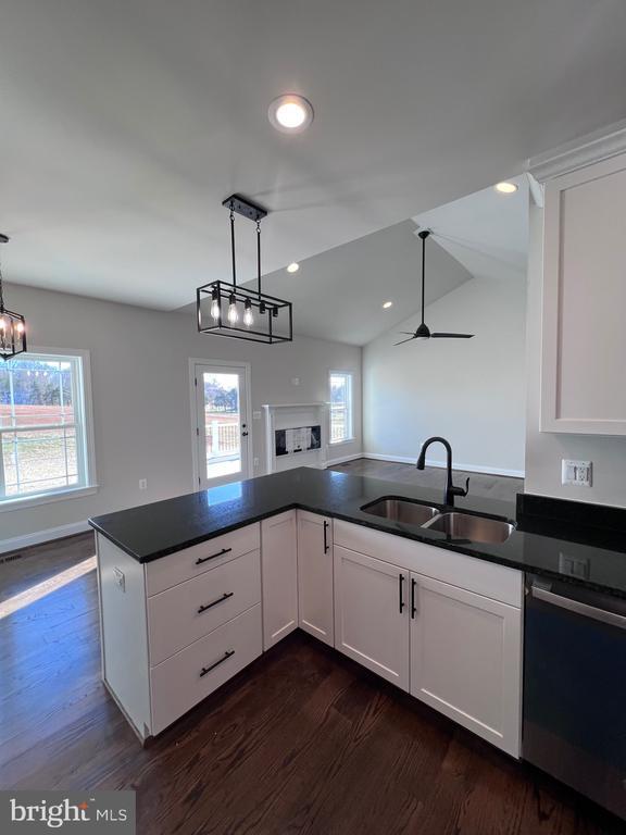 kitchen with pendant lighting, white cabinetry, dishwashing machine, and sink