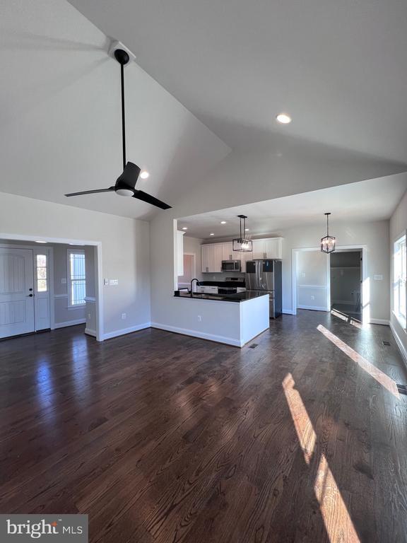 unfurnished living room featuring sink, dark wood-type flooring, high vaulted ceiling, and ceiling fan