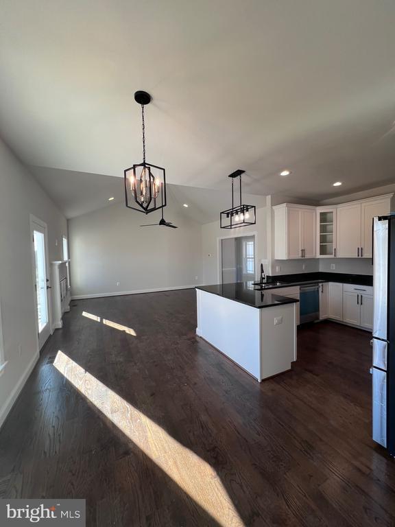 kitchen featuring pendant lighting, lofted ceiling, white cabinets, fridge, and stainless steel dishwasher