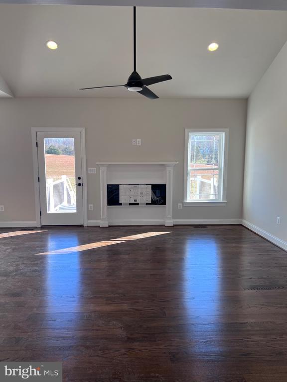 unfurnished living room featuring dark wood-type flooring and ceiling fan