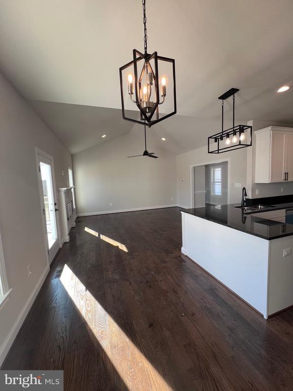 kitchen featuring dark hardwood / wood-style floors, pendant lighting, white cabinetry, lofted ceiling, and sink