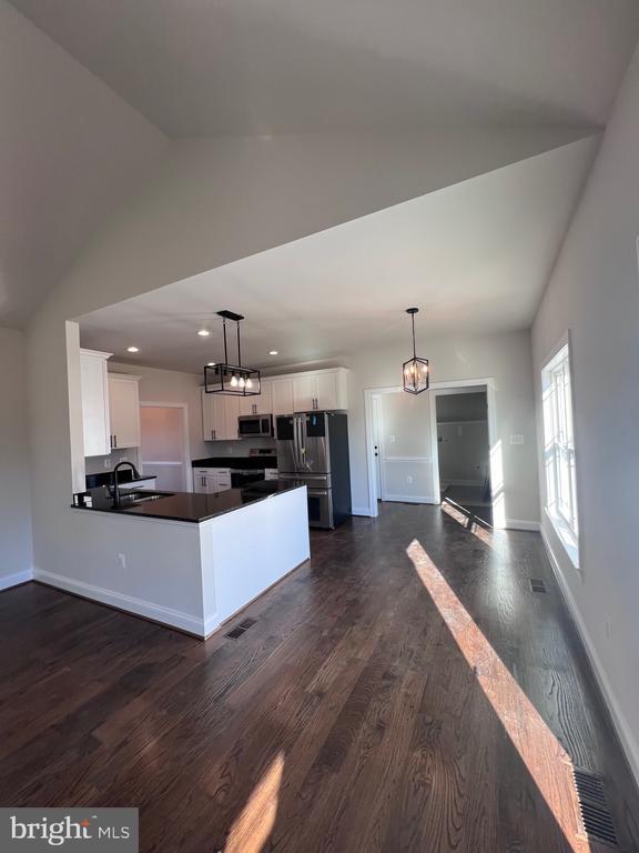 kitchen featuring decorative light fixtures, sink, white cabinets, dark hardwood / wood-style flooring, and stainless steel appliances