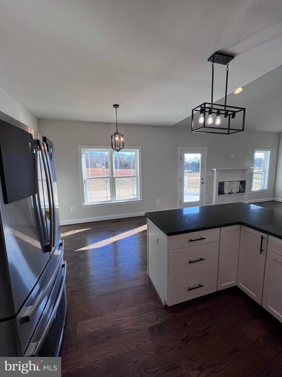 kitchen featuring a wealth of natural light, white cabinetry, hanging light fixtures, fridge, and dark wood-type flooring