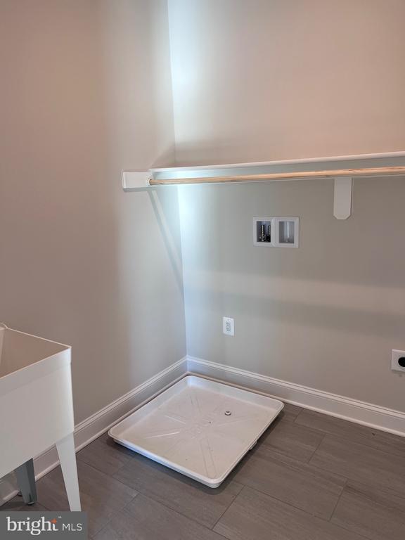 clothes washing area with hookup for a washing machine, electric dryer hookup, and dark hardwood / wood-style flooring