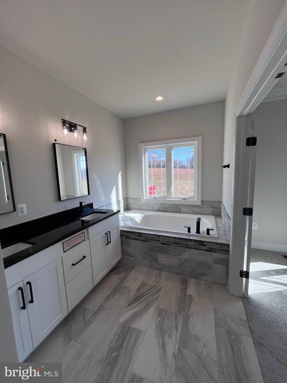 bathroom featuring vanity and tiled bath