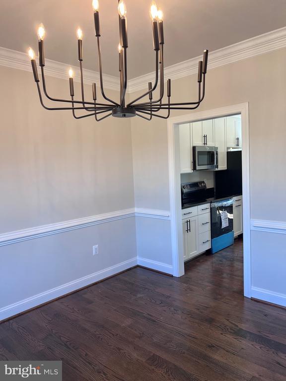 kitchen with crown molding, appliances with stainless steel finishes, dark hardwood / wood-style flooring, and white cabinets