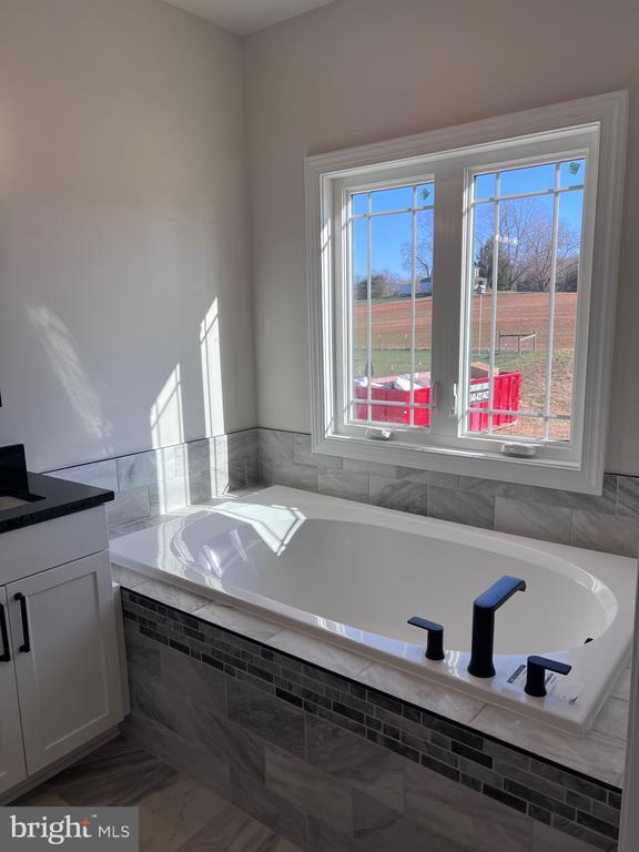 bathroom featuring a relaxing tiled tub and vanity