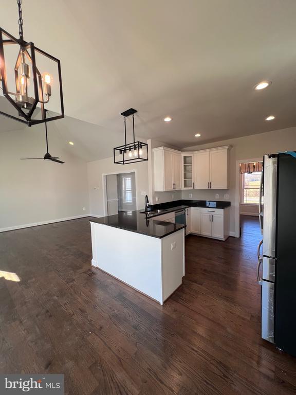 kitchen with stainless steel appliances, white cabinetry, dark wood-type flooring, and decorative light fixtures