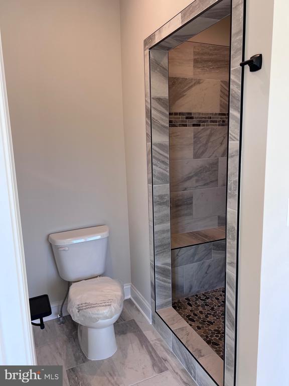 bathroom with a tile shower and toilet