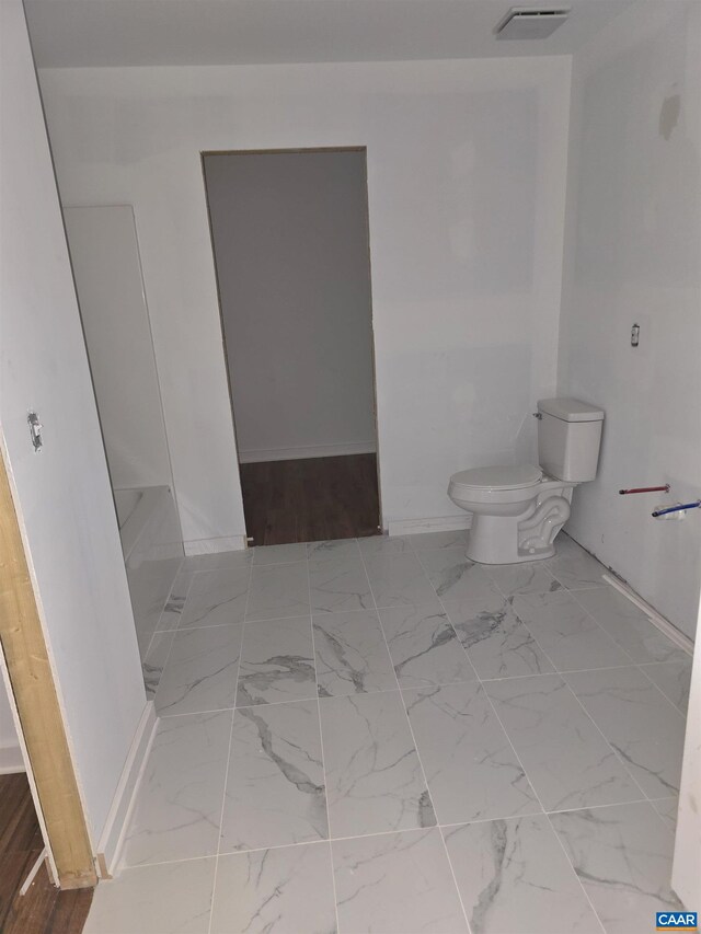 bathroom featuring visible vents, a bathing tub, toilet, and marble finish floor